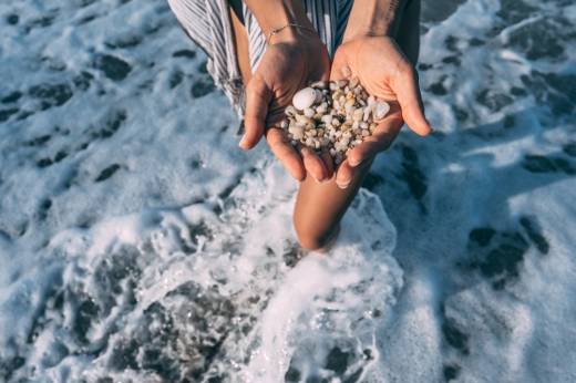 Women's hands are holding a lot of small pebbles of different shapes and sizes